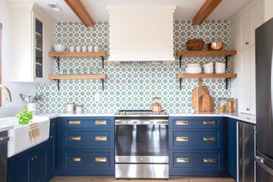 Inspiration for a mid-sized coastal u-shaped medium tone wood floor and exposed beam eat-in kitchen remodel in Other with a farmhouse sink, flat-panel cabinets, blue cabinets, quartz countertops, blue backsplash, cement tile backsplash, stainless steel appliances, an island and white countertops
