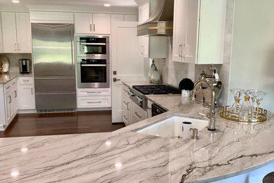 Example of a mid-sized transitional l-shaped brown floor and dark wood floor kitchen pantry design in Seattle with an undermount sink, shaker cabinets, white cabinets, quartzite countertops, white backsplash, marble backsplash, stainless steel appliances, an island and gray countertops