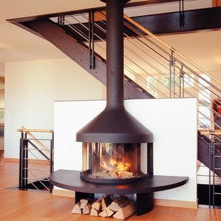 Exempel på ett modernt vardagsrum, med mellanmörkt trägolv och en öppen vedspis
