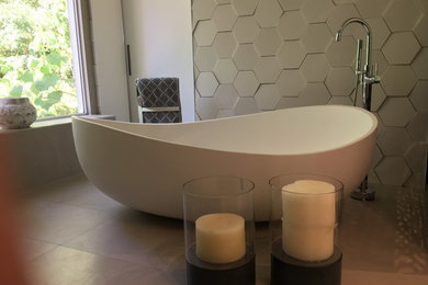 Inspiration for a large modern master bathroom in Sydney with raised-panel cabinets, white cabinets, a freestanding tub, an open shower, multi-coloured tile, stone tile, porcelain floors, a vessel sink and solid surface benchtops.