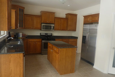 Inspiration for a mid-sized timeless l-shaped laminate floor and beige floor eat-in kitchen remodel in Other with a double-bowl sink, raised-panel cabinets, medium tone wood cabinets, granite countertops, stainless steel appliances, an island and gray countertops