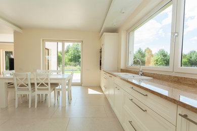 Example of a mid-sized tuscan ceramic tile eat-in kitchen design in Dallas with a double-bowl sink, recessed-panel cabinets, white cabinets and granite countertops