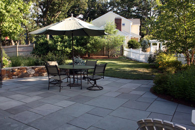 Example of a mid-sized classic backyard stone patio kitchen design in Boston with no cover
