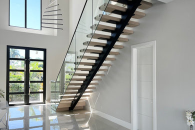 Foto de escalera recta minimalista grande sin contrahuella con escalones de madera y barandilla de vidrio