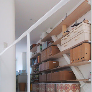 Modern inredning av ett mellanstort arbetsrum, med ett bibliotek, vita väggar, vinylgolv, ett inbyggt skrivbord och vitt golv