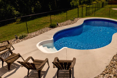 Diseño de piscina de tamaño medio en patio trasero con losas de hormigón