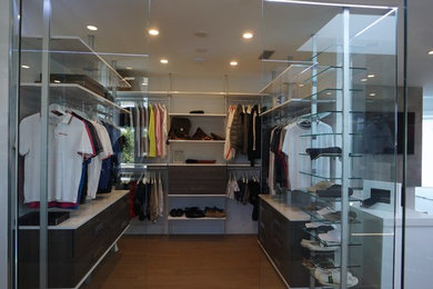 This is an example of a mid-sized modern gender-neutral walk-in wardrobe in Miami with open cabinets, dark wood cabinets and medium hardwood floors.