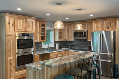 Mid-sized mountain style brown floor and vinyl floor eat-in kitchen photo in Other with an undermount sink, shaker cabinets, light wood cabinets, granite countertops, gray backsplash, glass tile backsplash, stainless steel appliances, an island and gray countertops