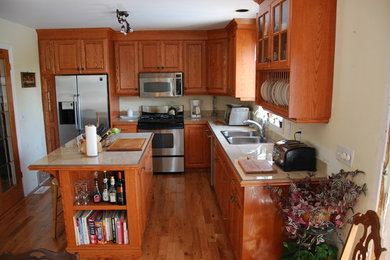 Inspiration for a mid-sized timeless l-shaped medium tone wood floor and brown floor kitchen remodel in Toronto with a drop-in sink, raised-panel cabinets, medium tone wood cabinets, stainless steel appliances, an island and beige countertops