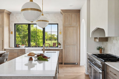 Eat-in kitchen - large modern light wood floor and brown floor eat-in kitchen idea in Minneapolis with a farmhouse sink, recessed-panel cabinets, light wood cabinets, quartz countertops, white backsplash, ceramic backsplash, paneled appliances, two islands and white countertops