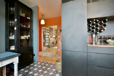Idée de décoration pour une cuisine américaine noire et bois tradition en U de taille moyenne avec un évier 1 bac, un placard à porte affleurante, des portes de placard noires, un plan de travail en bois, une crédence en carrelage métro, un électroménager noir, carreaux de ciment au sol, un sol multicolore et un plan de travail marron.