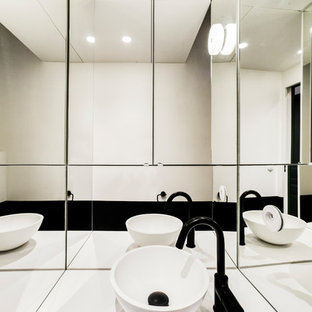 Ispirazione per un bagno di servizio minimal di medie dimensioni con ante lisce, ante nere, WC sospeso, piastrelle bianche, piastrelle a specchio, pareti nere, pavimento in cementine, lavabo a bacinella, top in quarzite, pavimento nero e top bianco