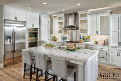Inspiration for a large contemporary l-shaped eat-in kitchen in Sacramento with an undermount sink, shaker cabinets, white cabinets, solid surface benchtops, white splashback, glass tile splashback, stainless steel appliances, light hardwood floors, with island, brown floor and white benchtop.