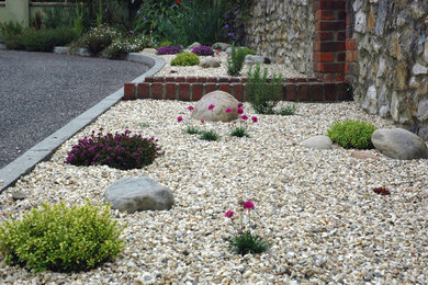 Inspiration for a small front yard full sun driveway for summer in Dorset with a garden path and gravel.