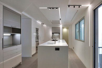 Diseño de cocina lineal contemporánea grande cerrada con fregadero de un seno, armarios con paneles lisos, puertas de armario blancas, suelo de baldosas de cerámica y una isla
