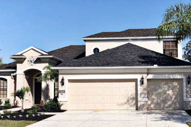 Photo of a large modern two-storey beige house exterior in Tampa with a hip roof and a shingle roof.