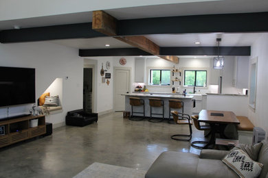 Immagine di un ampio soggiorno industriale con pareti bianche, pavimento in cemento, pavimento grigio e travi a vista