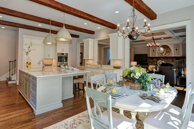 Example of a large classic medium tone wood floor kitchen design in DC Metro with a drop-in sink, white cabinets, marble countertops, beige backsplash, ceramic backsplash, stainless steel appliances and an island