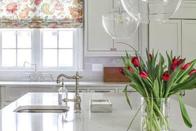 Inspiration for a timeless l-shaped medium tone wood floor and brown floor open concept kitchen remodel in Atlanta with a drop-in sink, white cabinets, quartz countertops, gray backsplash, ceramic backsplash, stainless steel appliances and an island