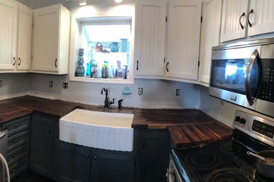Example of a small farmhouse kitchen design in Other with a farmhouse sink, recessed-panel cabinets, white cabinets, wood countertops, stainless steel appliances and no island