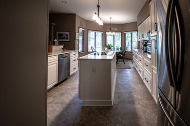 Eat-in kitchen - mid-sized transitional galley vinyl floor and gray floor eat-in kitchen idea in Cleveland with an undermount sink, shaker cabinets, white cabinets, quartz countertops, gray backsplash, ceramic backsplash, stainless steel appliances, an island and white countertops