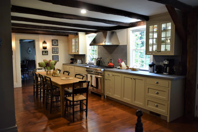 Mid-sized farmhouse galley medium tone wood floor and brown floor open concept kitchen photo in New York with a single-bowl sink, shaker cabinets, beige cabinets, quartz countertops, gray backsplash, stone slab backsplash, paneled appliances, no island and gray countertops