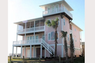 Ejemplo de fachada de casa rosa marinera grande de tres plantas con revestimiento de aglomerado de cemento y tejado a cuatro aguas