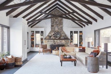 Example of a mountain style open concept slate floor, gray floor and exposed beam living room design in New York with white walls, a stone fireplace and a concealed tv