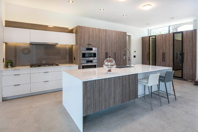 Inspiration for a contemporary l-shaped open concept kitchen remodel in Orlando with a farmhouse sink, flat-panel cabinets, quartz countertops, glass sheet backsplash, stainless steel appliances, an island and white countertops
