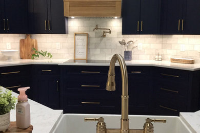 Example of a trendy u-shaped vinyl floor and brown floor open concept kitchen design in Other with a farmhouse sink, shaker cabinets, blue cabinets, quartz countertops, white backsplash, marble backsplash, stainless steel appliances, an island and white countertops