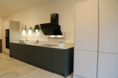 This is an example of a small modern single-wall open plan kitchen in Berkshire with a built-in sink, flat-panel cabinets, green cabinets, composite countertops, beige splashback, engineered quartz splashback, black appliances, laminate floors, no island, beige floors, beige worktops and feature lighting.