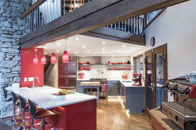 Inspiration for a mid-sized transitional u-shaped medium tone wood floor open concept kitchen remodel in Louisville with an undermount sink, flat-panel cabinets, red cabinets, quartz countertops, white backsplash, subway tile backsplash, stainless steel appliances and a peninsula