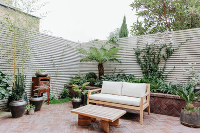 Small modern back patio in London with brick paving.