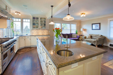 Photo of a traditional l-shaped open plan kitchen in Seattle with an undermount sink, beaded inset cabinets, white cabinets, granite benchtops, beige splashback and stainless steel appliances.
