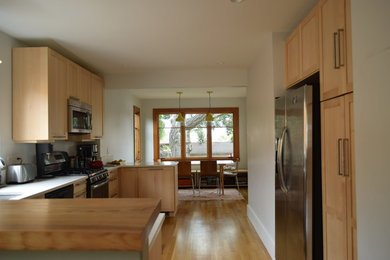 Inspiration for a mid-sized transitional u-shaped light wood floor and brown floor eat-in kitchen remodel in San Francisco with an undermount sink, shaker cabinets, light wood cabinets, quartz countertops, white backsplash, stainless steel appliances and a peninsula