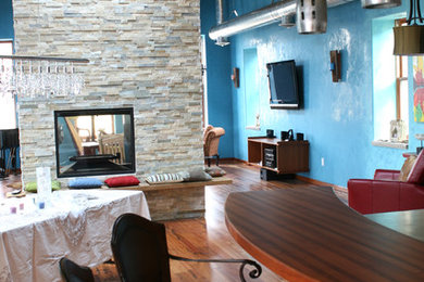 Inspiration for a mid-sized contemporary medium tone wood floor great room remodel in Minneapolis with blue walls, a two-sided fireplace and a stone fireplace