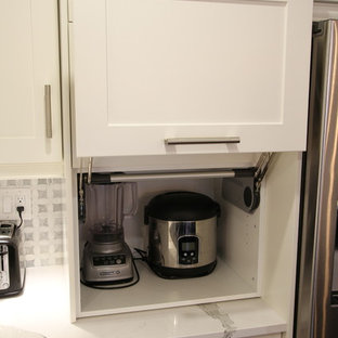 Идея дизайна: угловая кухня среднего размера в современном стиле с кладовкой, врезной раковиной, фасадами с утопленной филенкой, белыми фасадами, столешницей из кварцевого композита, серым фартуком, фартуком из плитки мозаики, техникой из нержавеющей стали, темным паркетным полом, островом и красным полом