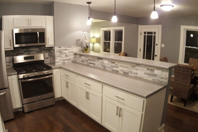 Modelo de cocina clásica renovada con puertas de armario blancas y electrodomésticos de acero inoxidable