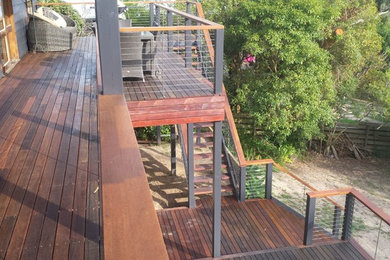 Photo of a large beach style backyard deck in Melbourne with a container garden and an awning.