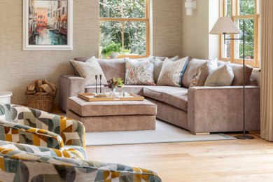 Large trendy open concept light wood floor and wallpaper living room photo in Other with beige walls, a corner fireplace and a plaster fireplace