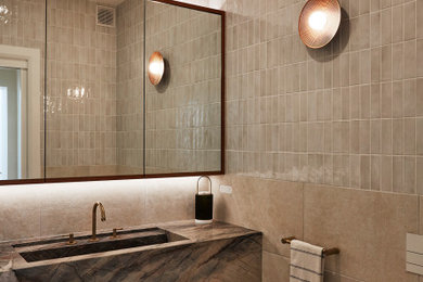 Design ideas for a mid-sized modern powder room in Sydney with flat-panel cabinets, brown cabinets, a wall-mount toilet, beige tile, porcelain tile, porcelain floors, an integrated sink, quartzite benchtops, beige floor, grey benchtops and a floating vanity.