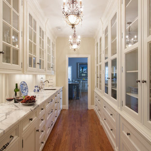 Идея дизайна: большая параллельная кухня в классическом стиле с кладовкой, стеклянными фасадами, белыми фасадами, мраморной столешницей, белым фартуком, техникой под мебельный фасад и паркетным полом среднего тона