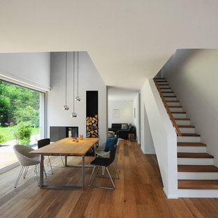 ニュルンベルクの中サイズのコンテンポラリースタイルのLDKの画像 (グレーの壁、無垢フローリング、両方向型暖炉、金属の暖炉まわり、茶色い床)