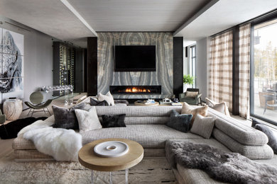 Offenes Modernes Wohnzimmer mit grauer Wandfarbe, hellem Holzboden, Gaskamin, Kaminumrandung aus Stein, TV-Wand und beigem Boden in Sonstige