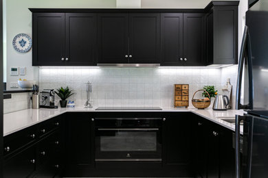 Photo of a contemporary kitchen in Other with a double-bowl sink, recessed-panel cabinets, black cabinets, quartz benchtops, white splashback, black appliances and white benchtop.