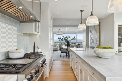 Example of a trendy u-shaped medium tone wood floor eat-in kitchen design in San Francisco with an undermount sink, recessed-panel cabinets, white cabinets, marble countertops, gray backsplash, ceramic backsplash, stainless steel appliances, an island and gray countertops