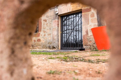 Ejemplo de fachada de casa ecléctica pequeña de dos plantas con revestimiento de piedra, tejado a doble faldón y tejado de teja de barro