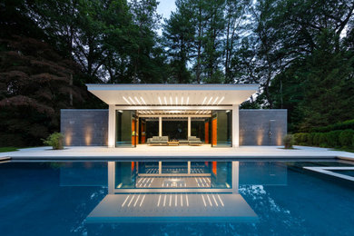 Example of a huge trendy backyard stone and custom-shaped pool house design in New York