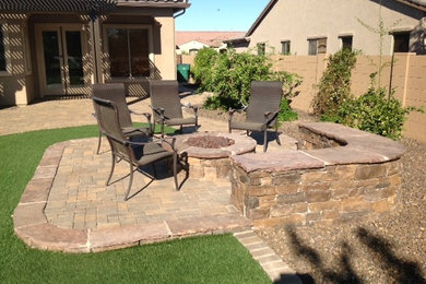 Example of a mid-sized mountain style backyard stone patio design in Phoenix with a fire pit and no cover