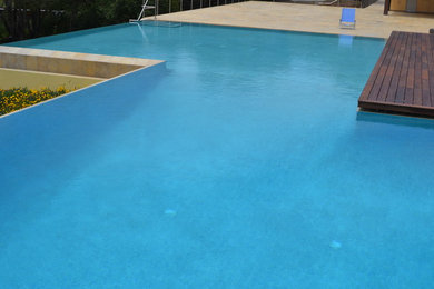 Large minimalist backyard stone and custom-shaped infinity pool photo in San Francisco